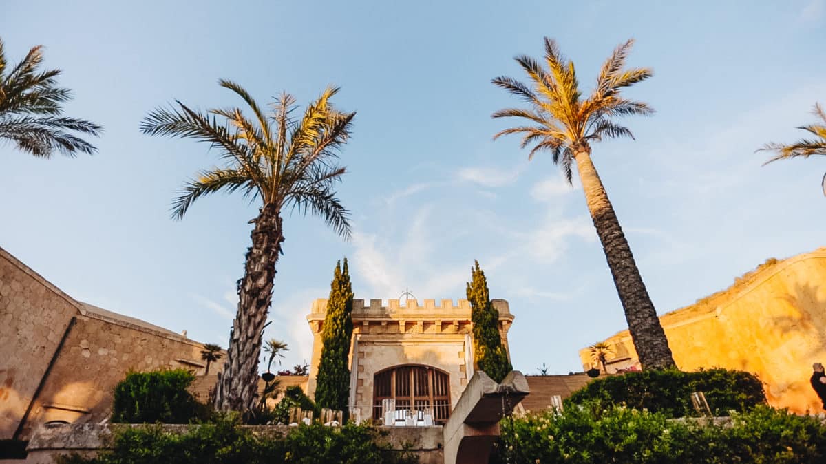 Cap Rocat wedding venue in Mallorca — historic fortress with palm trees and golden stone walls overlooking the Mediterranean — destination wedding film by HD Moments