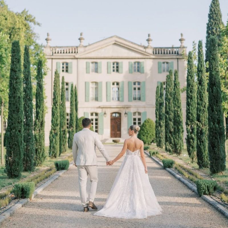 Bride Ellie and groom Alex walking together through the grounds of Château de Tourreau on their wedding day in Provence — photography by Sophie May